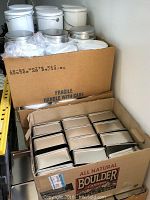 Boxes showing sets of square and round metal tins packed inside, confirming quantity as 24 square tins and 72 round tins.