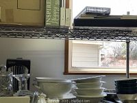 Shelf with stacked white ceramic bowls, dark blue bowls, and large white soup tureen with lid and underplate.