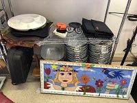 Wire shelf showing folded Crate & Barrel table linens, white divided serving platter, and partial view of Porter Cable framing nailer tool behind.