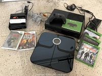 All items arranged on floor: scale, consoles, controllers, games and cables