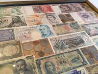 Framed collage showing a variety of international paper currency and loose coins from countries including Canada, Mexico, UK, Vietnam, and others from Asia and South Pacific regions.