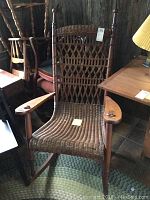 Front view of the large woven wicker rocking chair showing wooden arms, spindles, and the woven seat and backrest.