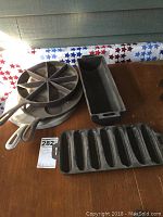Photo showing full set of five cast iron cookware pieces including divided corn bread pan, rectangular baking dish and multiple round skillets.
