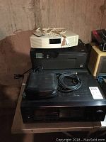 Five electronic items stacked: beige Bose stereo clock on top, black HP DeskJet 3520 printer beneath, black Philips CD changer at bottom, plus black CD case and cables on Philips unit.