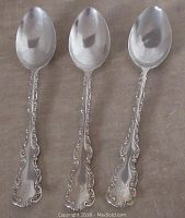 Photo of the front side of three matching sterling silver spoons showing ornate handles and monogram near the handle ends.