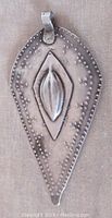 Front view of the teardrop-shaped sterling silver pendant showing raised central oval, diamond shape and dotted pattern.