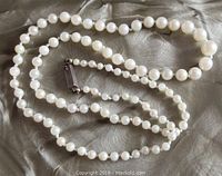 Full length of necklace laid out on fabric showing pearl sizing and sterling clasp