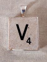 Front view of a square pendant featuring the letter 'V' and the number '4' styled as a Scrabble tile.