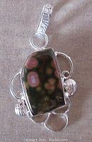 Close-up front view of the contemporary sterling silver pendant with Ocean Jasper stone showing orange orb patterns and silver wire decorative elements.