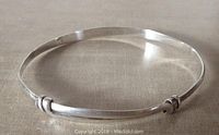 Full front view of the sterling silver engraved bangle lying flat showing shape, engraving plate, and expansion mechanism.