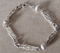 Sterling silver bracelet displayed flat on fabric, showing the ribbed beads and openwork links clearly, including the spring ring clasp and the 925 marking.