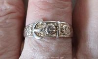Close-up front view of the vintage sterling silver ring showing the detailed buckle motif design with floral accents, worn on a finger.