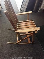 Side view of the vintage hardwood patio rocking chair showing slatted seat and rocker base.