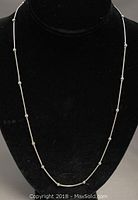 Full front view of the sterling silver beaded necklace displayed on black jewelry bust showing chain and beads spaced along it.