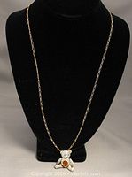 Photo of the full gold-tone linked chain with the teddy bear pendant worn on black display bust
