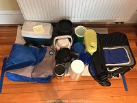 Various insulated lunch bags, coolers, and plastic tumblers grouped on the floor