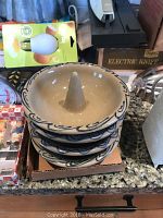 Stacked ceramic apple bakers and Bundt pans on granite countertop with other kitchenware.