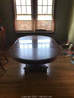 Full view of the oval wooden dining table showing top surface and pedestal base.