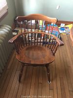 Image showing one claw-armed captain chair with curved armrests and spindle back, wooden seat, and floor with wooden planks.