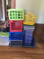 Stack of various colored plastic crates and storage containers, including a yellow basket on top.