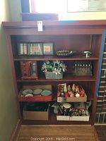 Wooden shelving holding multiple collectible items including nesting dolls, decorative plates, vintage phones, and wooden box.