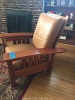 Front-side view of recliner chair showing leather upholstered cushions and wood frame