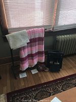 Full view of vintage shoeshine box, quilt rack holding afghan and lace cloth, accessories on wooden floor.