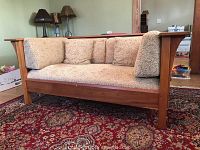Front angled view of the loveseat showing seat cushion, three back cushions, and cherry wood frame