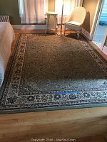 Full view of green and cream floral rug in room setting