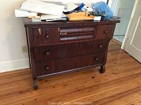 Front view of the vintage six drawer dresser with some scratches and items on top.