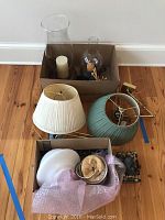 Overview of lamps, lampshades, glass hurricane candle holders, and globe light fixture showing arrangement and condition