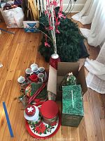 Wide view of Christmas decor collection showing wreaths, mugs, tins, ribbons, gift boxes, and ceramic Christmas tree