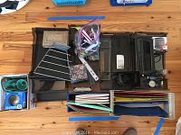 Top view of assorted office supplies laid out on wooden surface including file organizers, notebooks, hole puncher, tape dispenser, pens, and rulers.