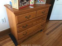Right-side angle of oak wood dresser displaying three drawers with metal handle pulls and natural wood grain finish.