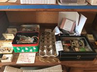 Full overview of desk showing costume jewelry boxes, tin container, watch organizer, and other items including chains and bracelets.