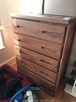 Front view of the wood dresser showing five drawers and marks on surface.