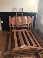 Stack of wooden headboards, footboards and ladder leaning against wall