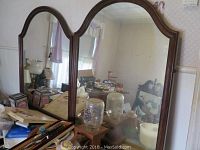 Photo of three wall mirrors set on a dresser showing all three mirrors with wooden frames and reflective glass surface.