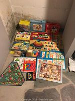 Photo showing multiple children's puzzles including alphabet, animals, counting puzzles, and wooden building blocks.