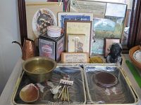 Photo showing assortment of decorative and household items including framed prints, metal pitcher, earthenware pot, a bust sculpture, and the boxed glass tree frog.