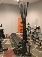 Image showing Bowflex Power Pro with foldable bench, vertical resistance rods and attached cables in a stone floor room.