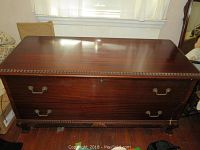 Closed view of Lane cedar trunk showing rich polished wood with brass handles and footed base