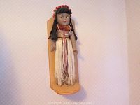 Full front view of the Hawaiian hula doll mounted on a wooden display stand showing the entire doll and base.