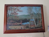 Full view of framed landscape picture showing autumn scene with trees and mountains, mounted on wall.