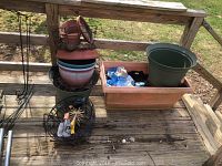 View of all plastic flower pots, including large rectangular wheeled planter, stacked round pots, and wire hanging baskets on wooden deck