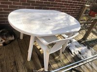 Plastic patio table and chair with visible soiling and discoloration on a wooden deck
