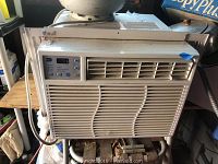 Front view of GE window air conditioner installed, showing the air vent and control panel area.