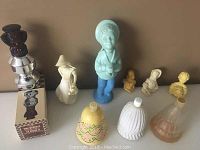 Photo of Avon collectible figurines and bottles arranged in a row on a shelf including a tall boy figurine, busts, and shaped bottles