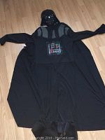Full laid-out photo of the Darth Vader costume jumpsuit with attached cape spread flat on floor.