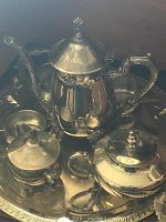Close-up image of silverplated teapot, sugar bowl, creamer on detailed silver tray.